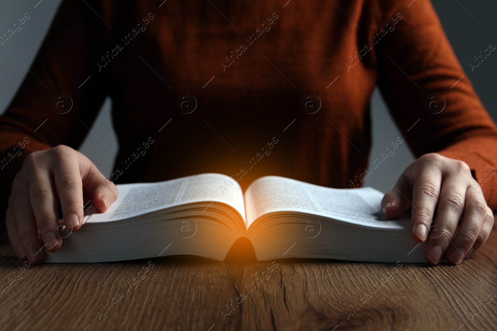 Photo of Woman reading Bible at wooden table, closeup