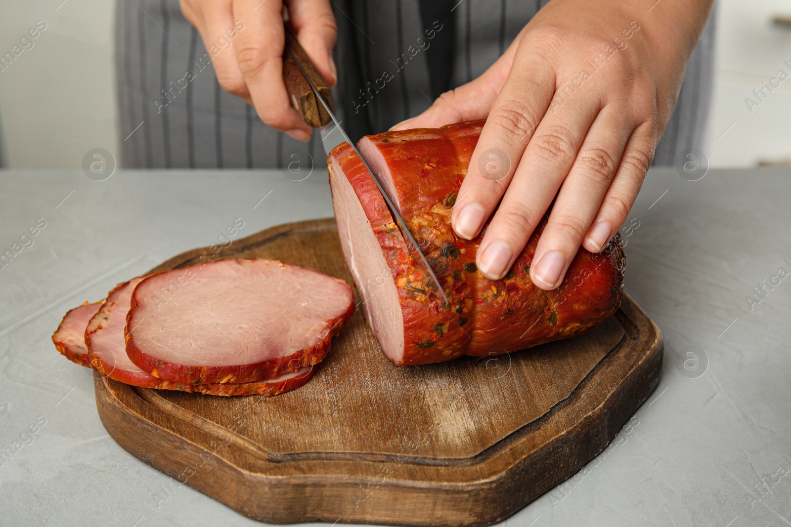 Photo of Woman cutting ham at table in kitchen, closeup