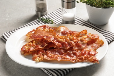 Plate with fried bacon on table