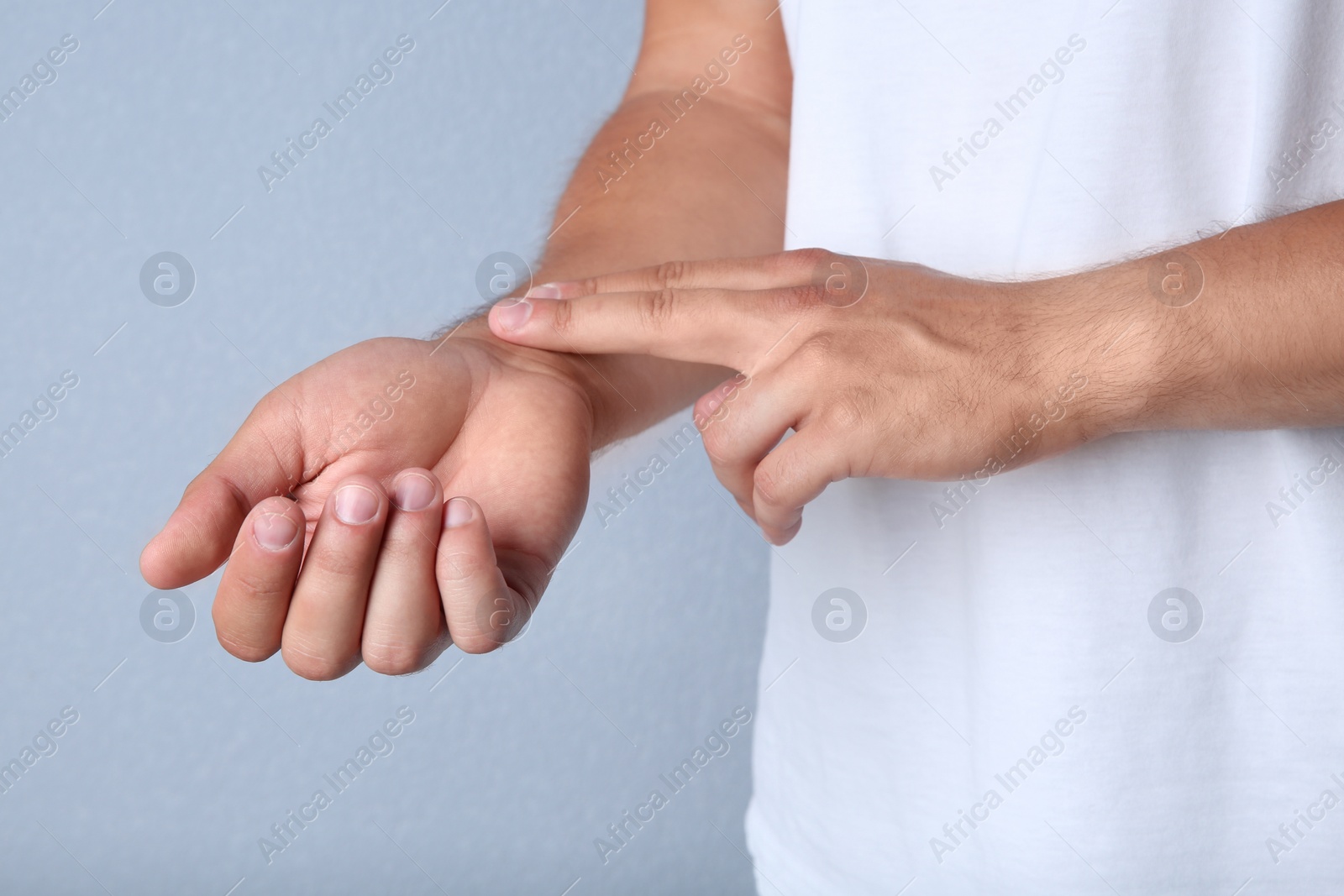 Photo of Young man checking pulse on color background