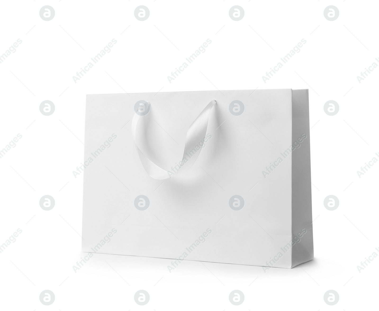 Photo of Paper shopping bag with ribbon handles on white background. Mockup for design