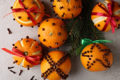 Pomander balls made of tangerines with cloves and fir branches on grey table, flat lay