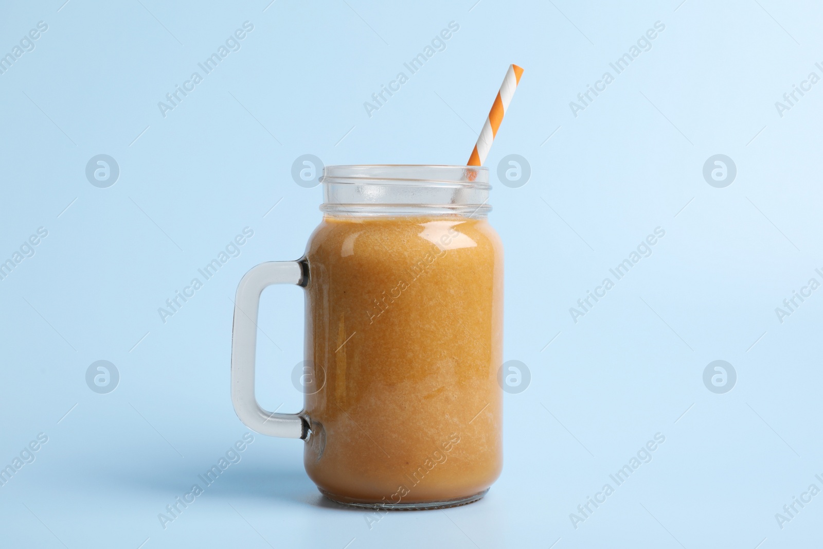 Photo of Mason jar with delicious fruit smoothie on light blue background