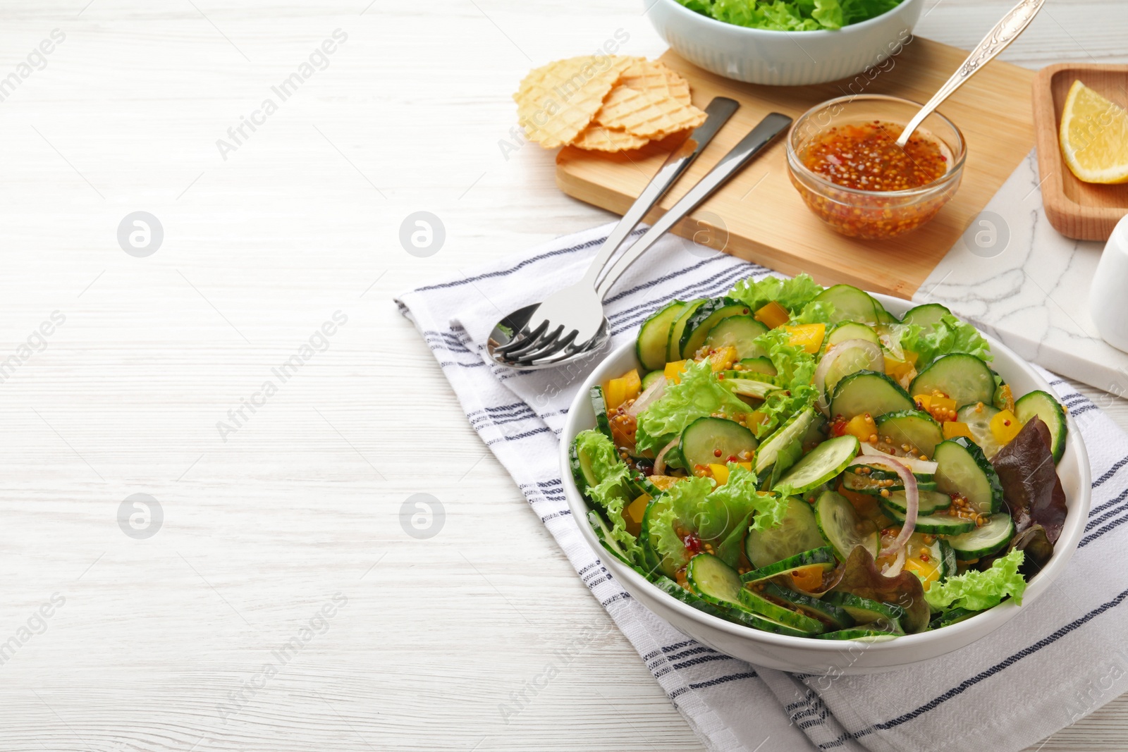 Photo of Delicious cucumber salad served on white wooden table. Space for text