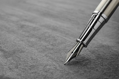 Photo of Stylish silver fountain pen on grey textured table, closeup. Space for text