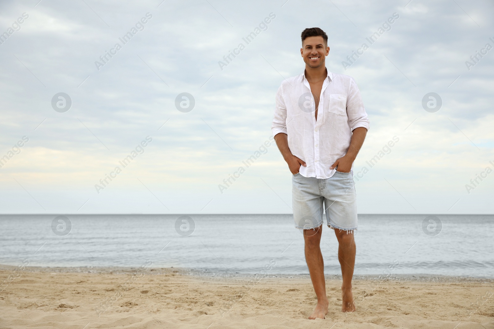 Photo of Handsome man on beach near sea. Space for text