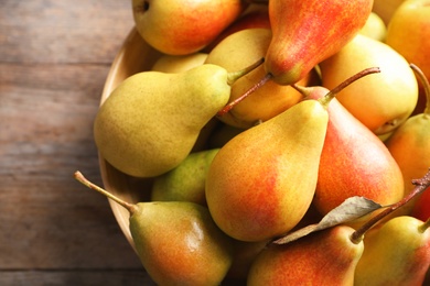 Bowl with ripe pears on wooden background, closeup