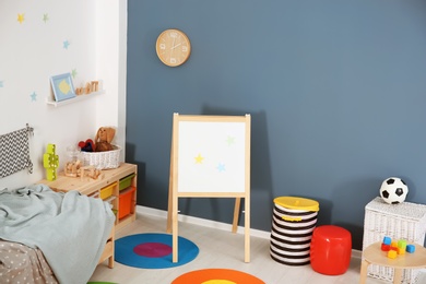 Photo of Modern child room interior with comfortable bed and flip chart board