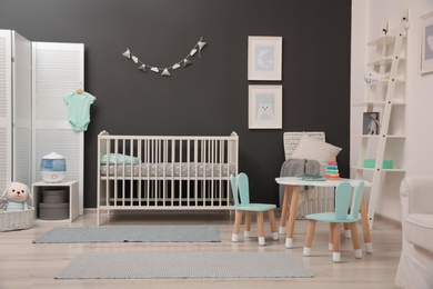 Photo of Cute baby room interior with modern crib near dark wall