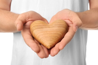 Photo of Young man holding wooden heart on white background, closeup. Donation concept