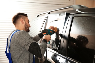 Photo of Worker tinting car window with heat gun in shop