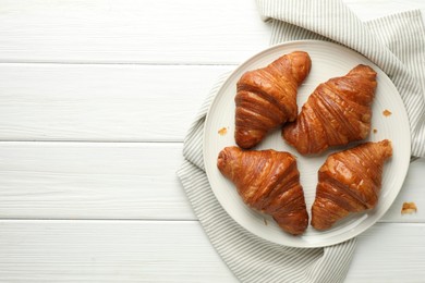 Photo of Plate with tasty croissants on white wooden table, top view. Space for text