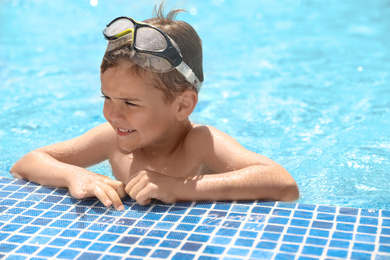 Photo of Little boy wearing diving mask in swimming pool. Summer vacation