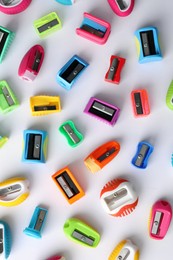 Photo of Many different colorful sharpeners on white background, flat lay. Diversity concept