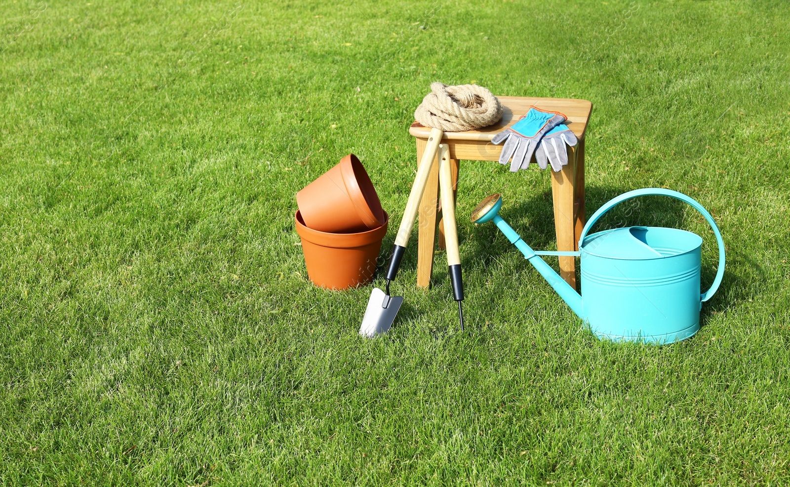 Photo of Set of gardening tools and stool on green grass