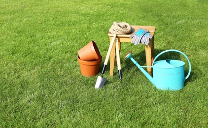 Set of gardening tools and stool on green grass