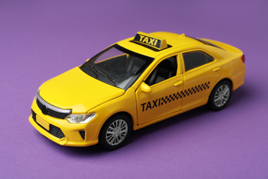 Photo of Yellow taxi car model on purple background