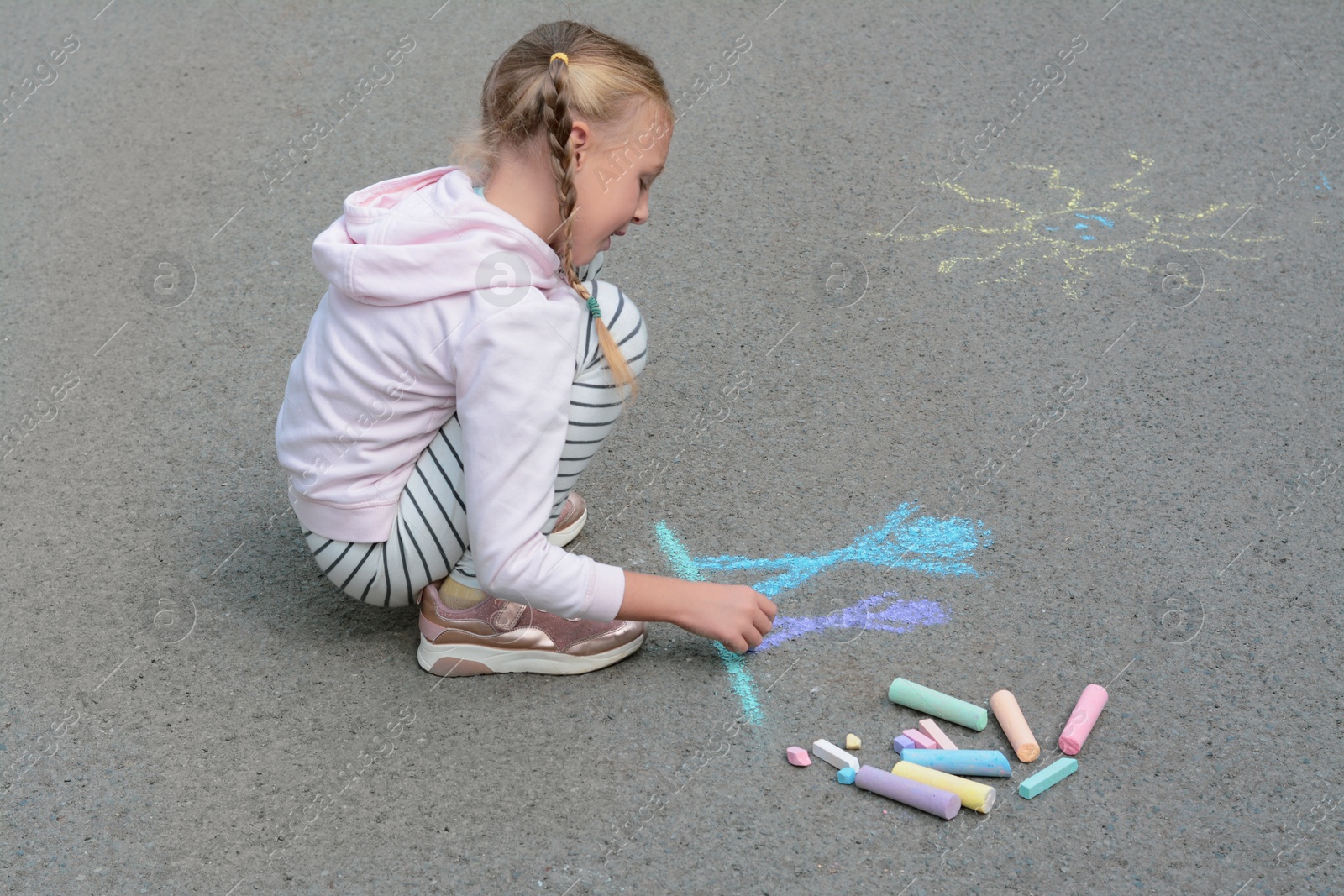 Photo of Little child drawing happy family with chalk on asphalt