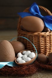 Photo of Delicious chocolate Easter eggs and ribbon on wooden table, closeup