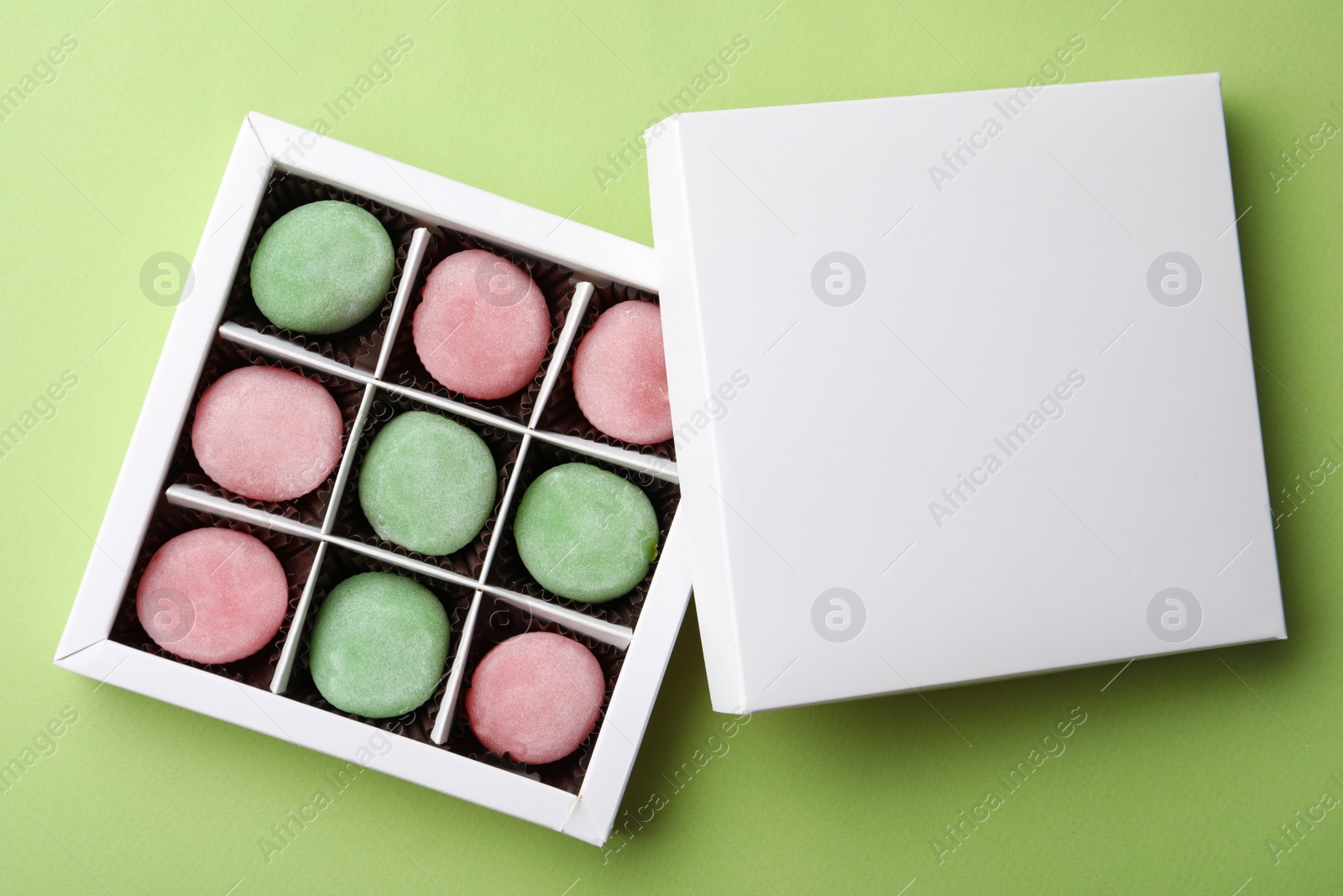 Photo of Many different delicious mochi in box on green background, top view. Traditional Japanese dessert