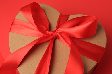Photo of Beautiful heart shaped gift box with bow on red background, closeup