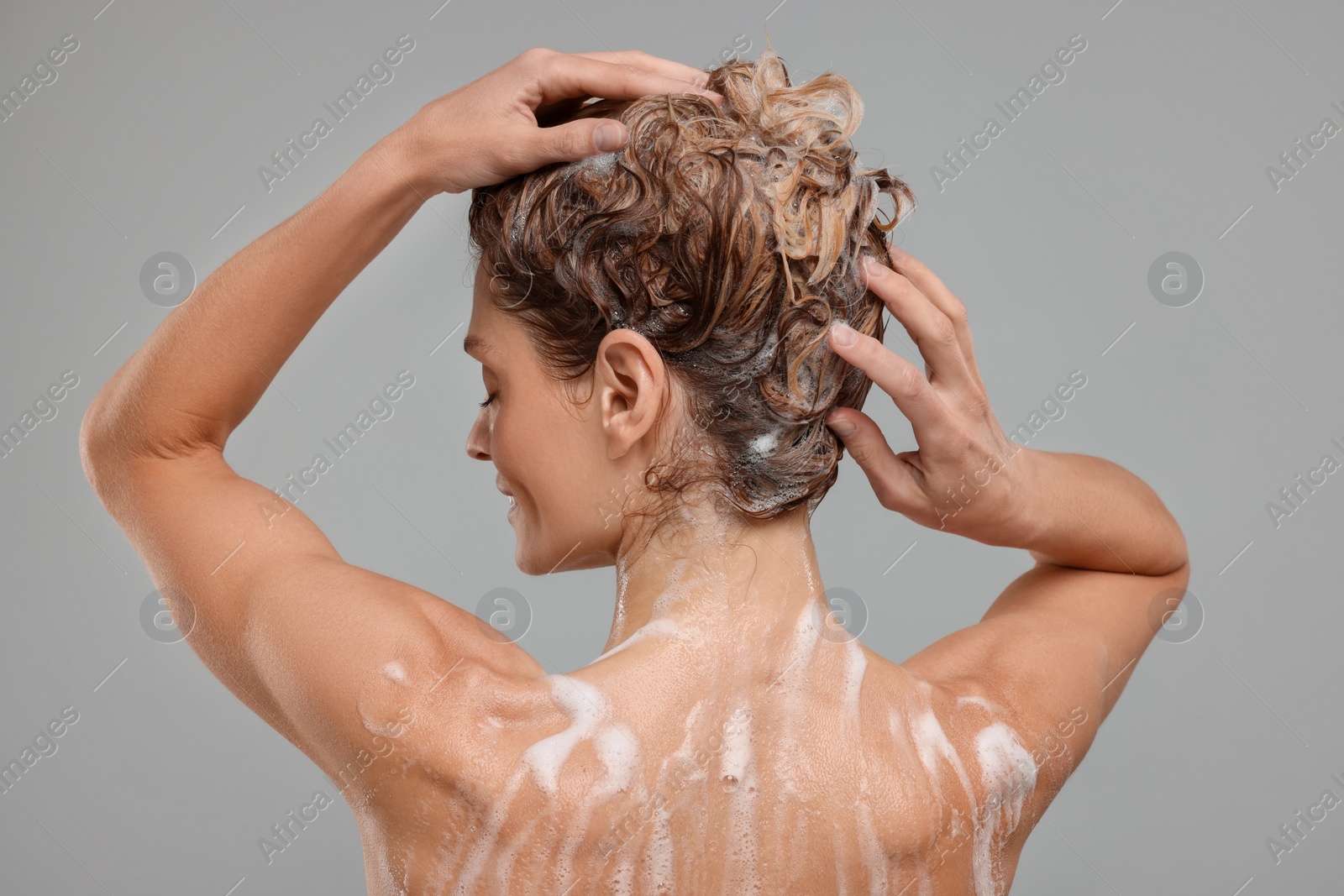 Photo of Woman washing hair on light grey background, back view