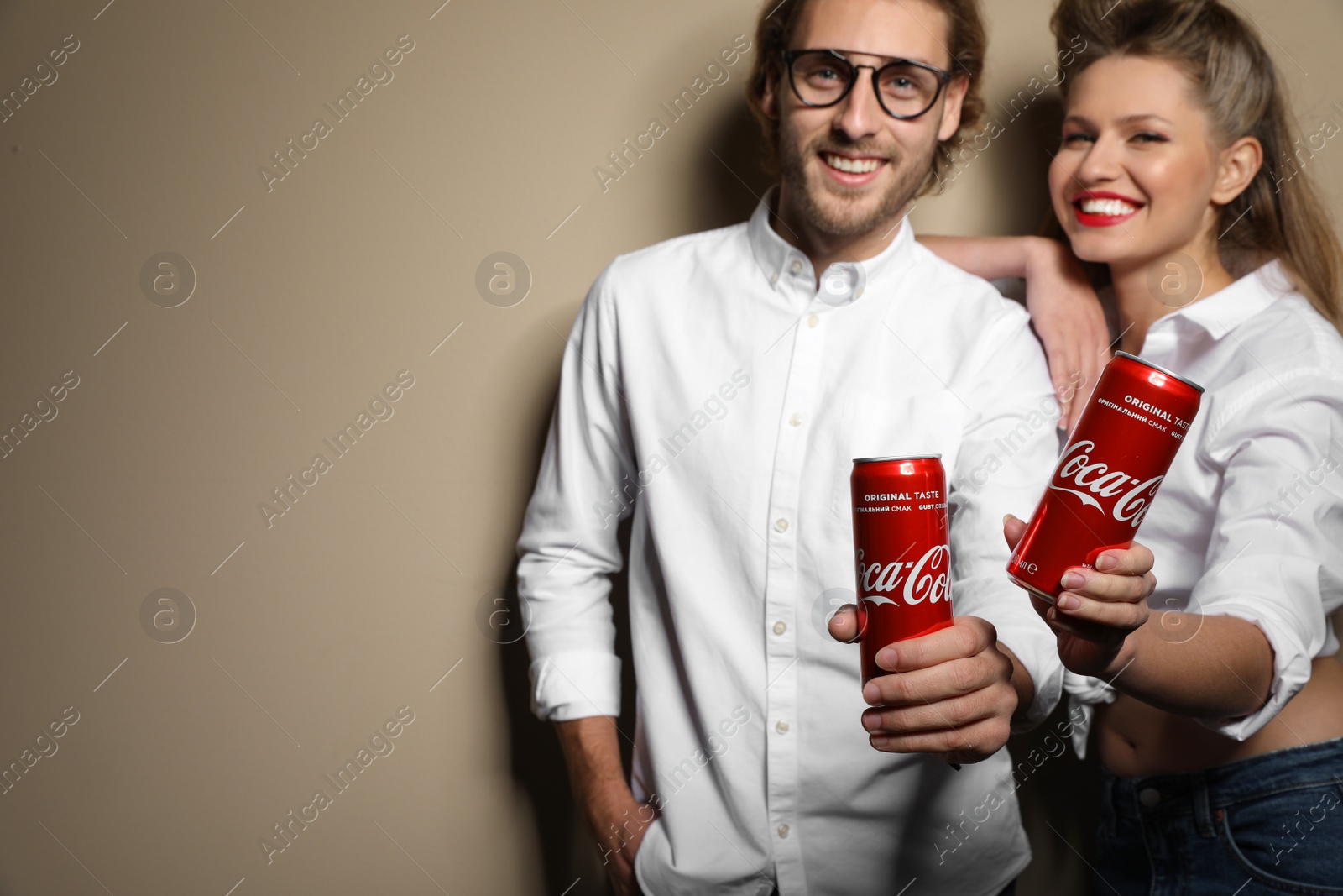 Photo of MYKOLAIV, UKRAINE - NOVEMBER 28, 2018: Young couple with Coca-Cola cans on color background, space for text