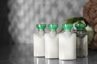 Photo of Mini bottles of cosmetic products on grey textured table, space for text