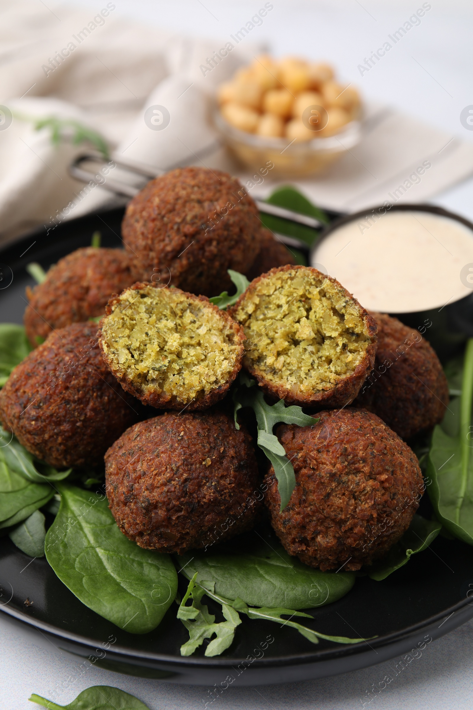 Photo of Delicious falafel balls, herbs and sauce on table