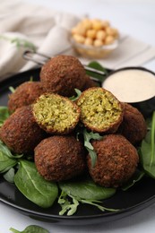 Photo of Delicious falafel balls, herbs and sauce on table