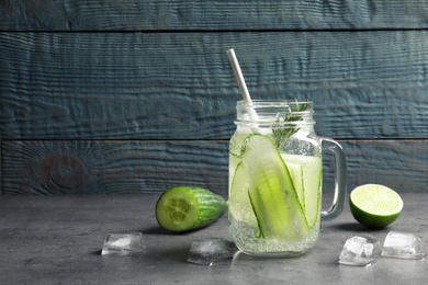 Photo of Mason jar with fresh cucumber water on table. Space for text