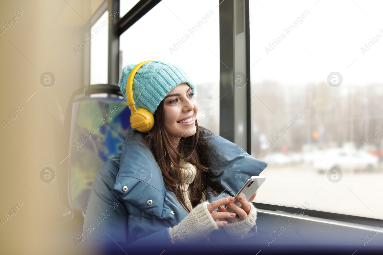 Photo of Young woman listening to music with headphones in public transport