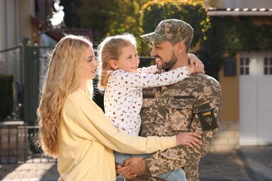 Soldier in Ukrainian military uniform reunited with his family on city street