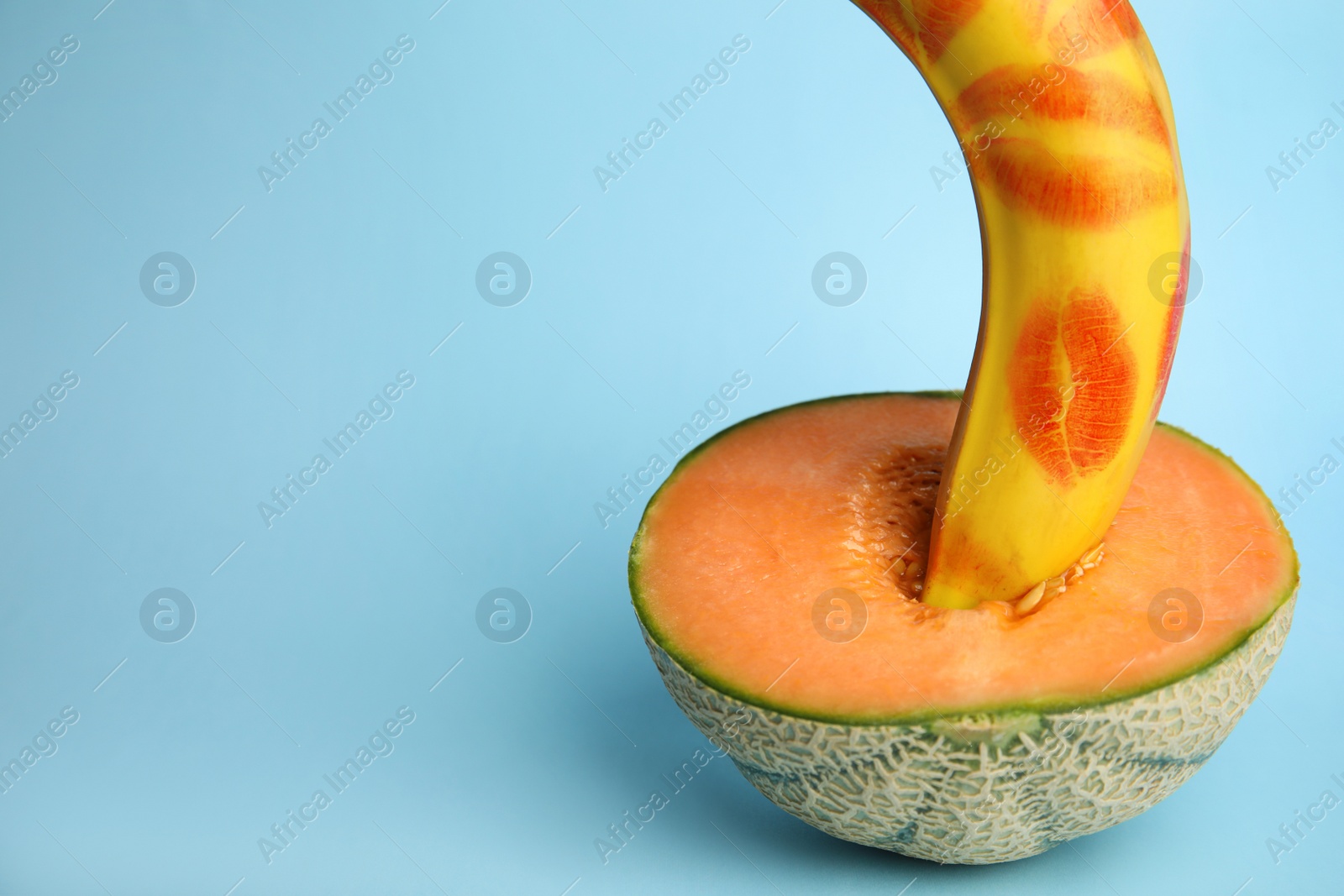 Photo of Fresh banana with red lipstick marks and melon on blue background, space for text. Sex concept