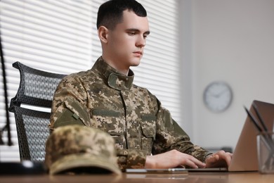 Military service. Young soldier working with laptop at table in office