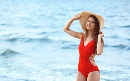 Photo of Attractive young woman in beautiful one-piece swimsuit on beach