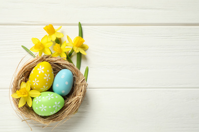 Photo of Flat lay composition with Easter eggs on white wooden background. Space for text