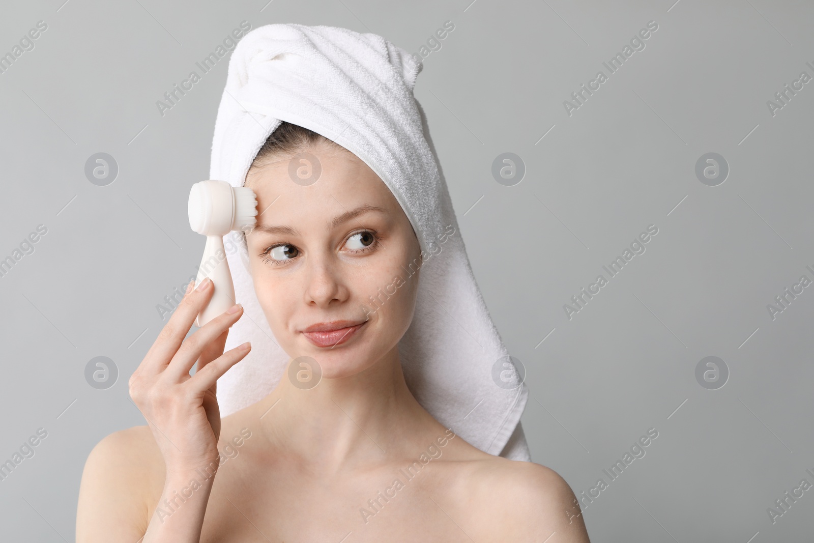 Photo of Washing face. Young woman with cleansing brush on grey background, space for text