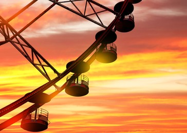 Image of Beautiful large Ferris wheel outdoors at sunset