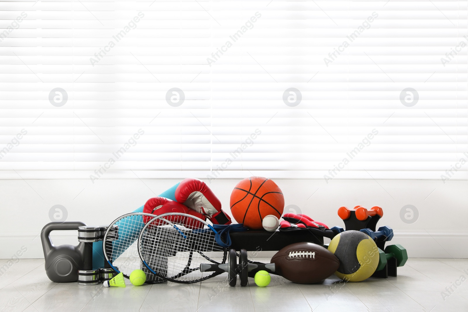 Photo of Set of different sports equipment on white floor indoors, space for text