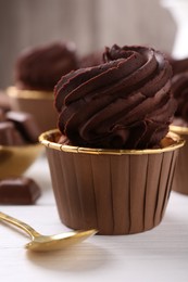 Delicious chocolate cupcake on white wooden table, closeup