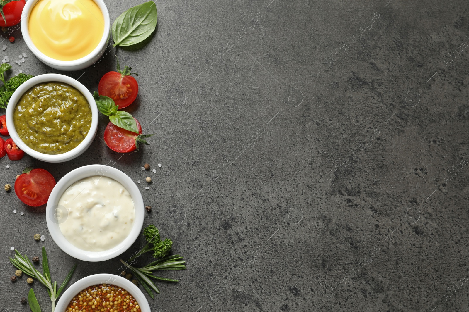 Photo of Bowls with different sauces and ingredients on gray background, flat lay. Space for text