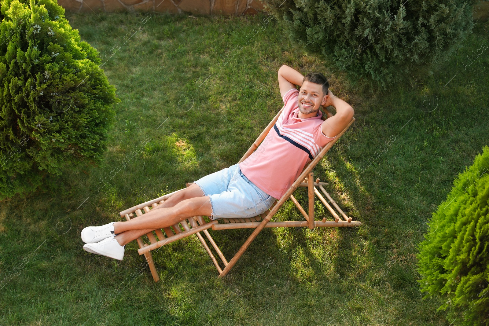 Image of Happy man resting in deck chair outdoors, above view