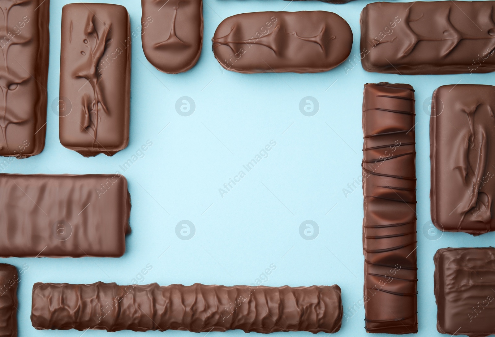 Photo of Different tasty chocolate bars on light blue background, flat lay. Space for text