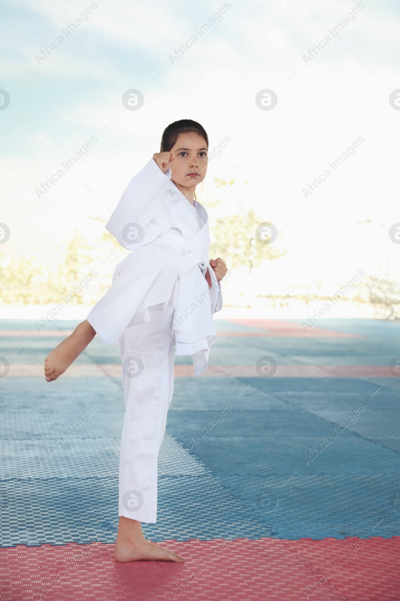 Photo of Girl in kimono practicing karate on tatami outdoors