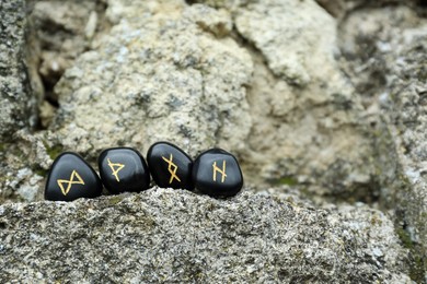 Photo of Black runes on stone outdoors. Space for text