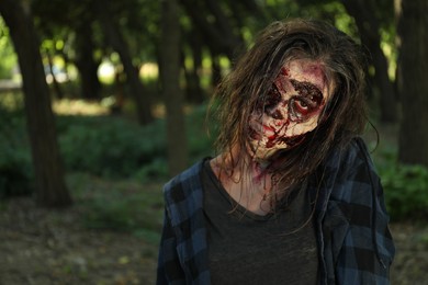 Photo of Scary zombie with bloody face outdoors. Halloween monster