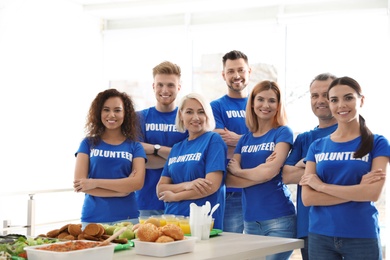 Team of volunteers near table with food indoors