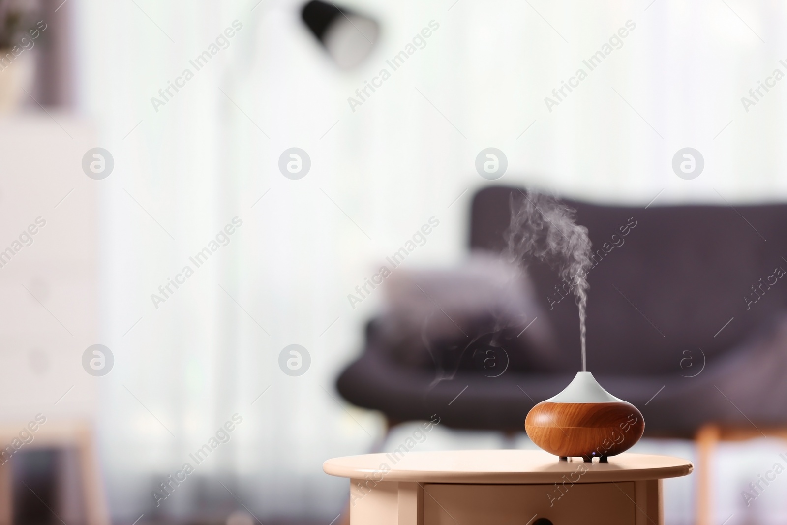 Photo of Aroma oil diffuser on table against blurred background. Air freshener