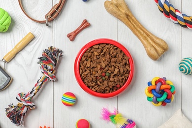 Photo of Bowl with food for cat or dog and accessories on wooden background. Pet care